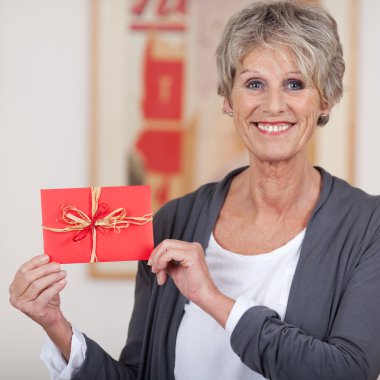 Smiling elderly woman showing a decorated envelope clipart