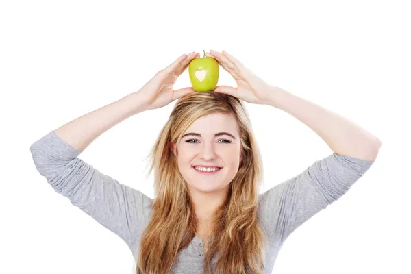 Usměvavá blondýnka dospívající drží zelené jablko na hlavu — Stock fotografie