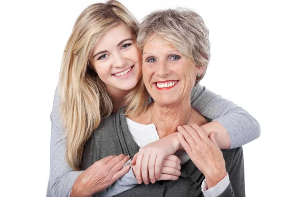 Happy Teenage Girl Embracing Grandmother From Behind — Stock Photo, Image