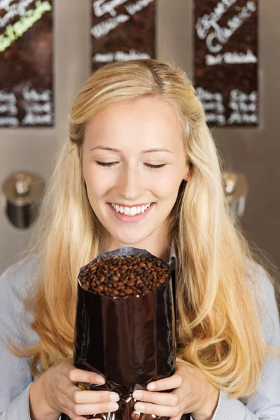 Salesgirl holding package of coffee beans — Stock Photo, Image