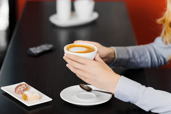 Vrouw handen met koffiekopje aan tafel — Stockfoto