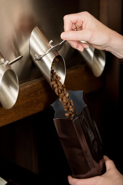 Verkoopster koffie bonen in zak te vullen — Stockfoto