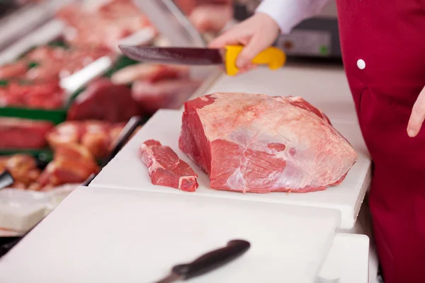 Vendedora cortando carne a bordo no balcão — Fotografia de Stock