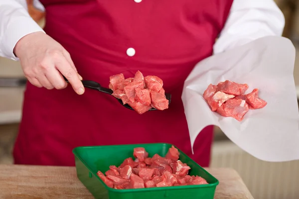 Slaktare packning köttbitarna i papper på butik — Stockfoto