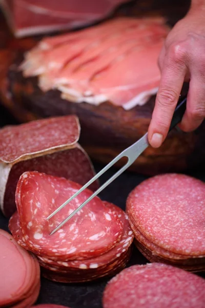 Carnicero recogiendo embutido con tenedor de carne — Foto de Stock