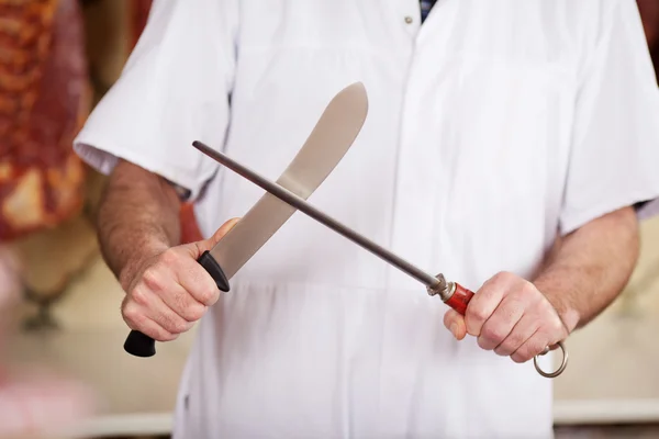 Metzger schärft Messer in Geschäft — Stockfoto