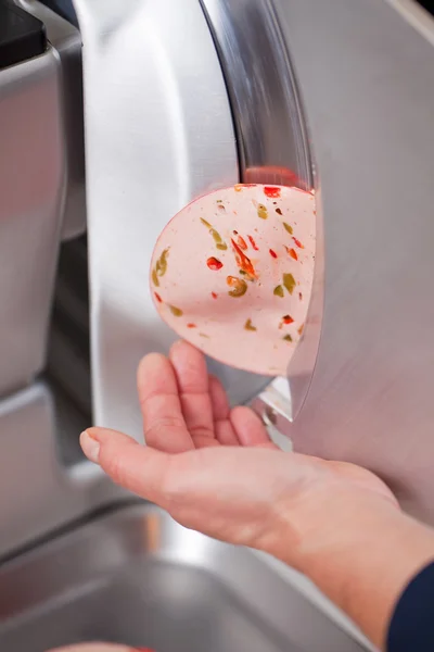 Manos de carnicero tocando salami saliendo de la máquina — Foto de Stock