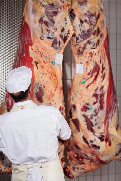 Carnicero de pie frente a la carne en la tienda — Foto de Stock