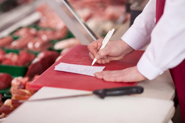 Butcher Writing On Paper At Counter — Stock Photo, Image