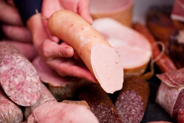 Metzgerhände zeigen Wurst im Laden — Stockfoto