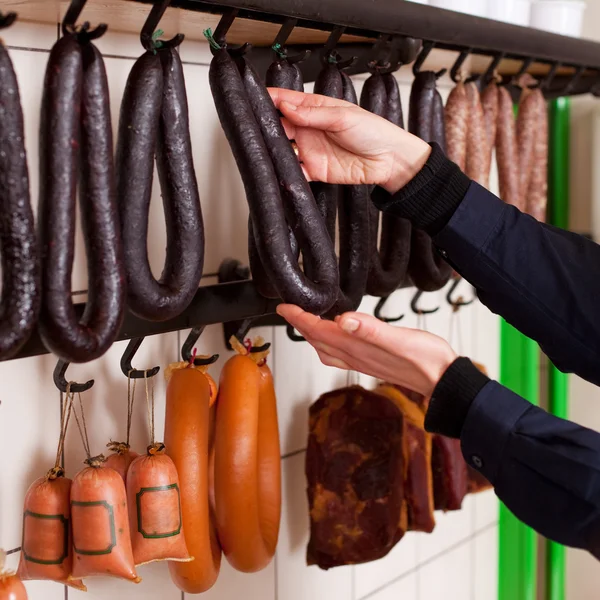 Açougueiro Organizar salsichas em ganchos — Fotografia de Stock