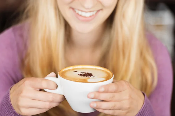 Femme souriant tout en tenant tasse de café — Photo