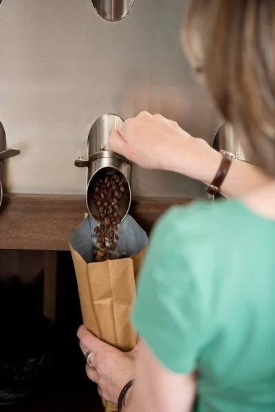 Serveerster koffie bonen in papieren zak te vullen — Stockfoto