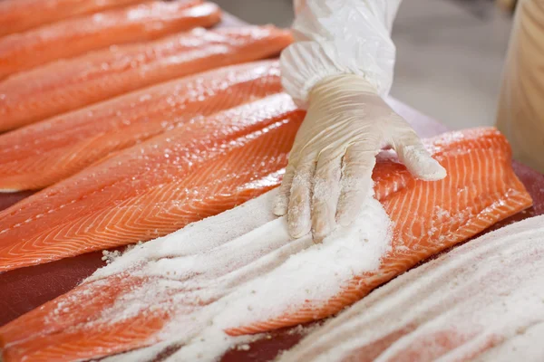 Aplicación manual de sal sobre los peces en rodajas en la mesa —  Fotos de Stock