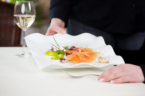 Garçonete servindo prato de salmão para o cliente na mesa — Fotografia de Stock