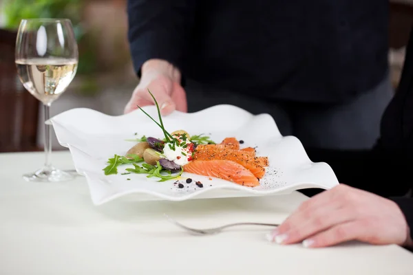 Waitress serving tasty fish dish — Stock Photo, Image