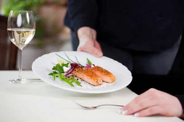 Empregada de mesa que serve salmão — Fotografia de Stock