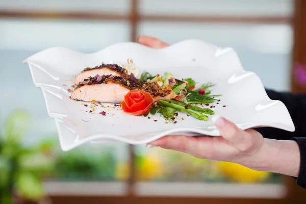 Mani della cameriera che tengono piatto di salmone nel ristorante — Foto Stock