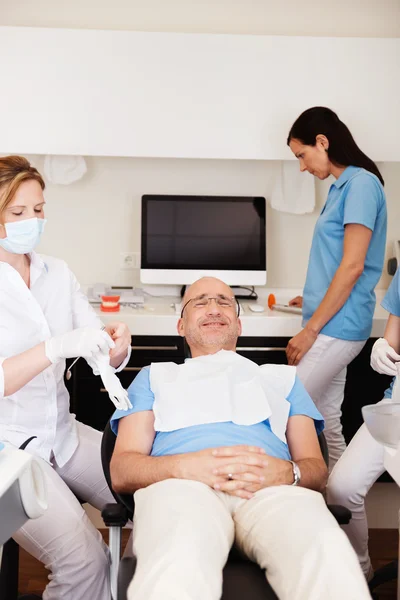 Paciente retrocediendo en silla dental mientras los dentistas se preparan para C — Foto de Stock