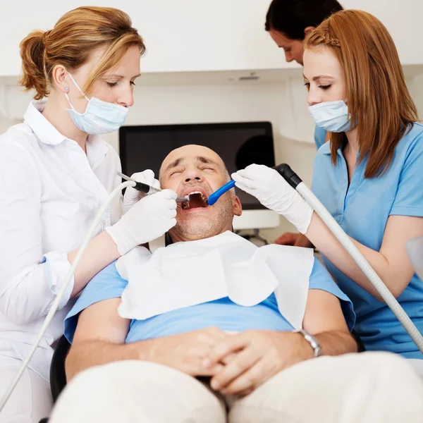 Dentistas examinando a boca do homem na clínica — Fotografia de Stock