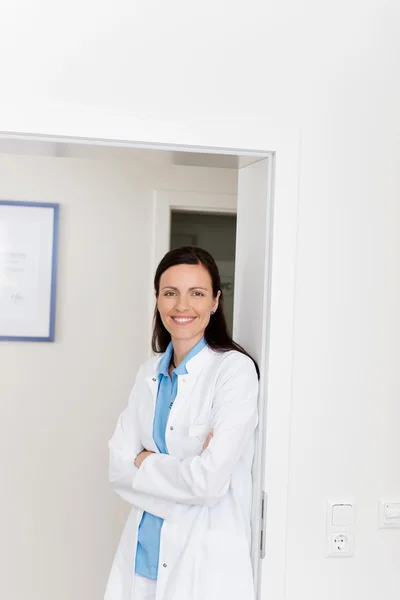 Dentista femenina con los brazos cruzados apoyada en la puerta — Foto de Stock