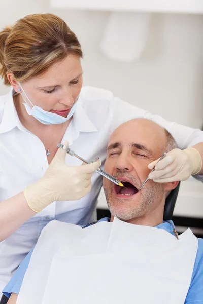 Врач-стоматолог вводит пациенту анестезию перед лечением — стоковое фото