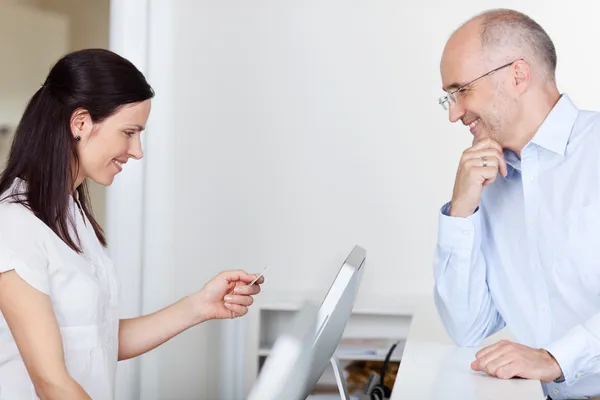 Empfangsdame schaut auf Ausweis des Patienten — Stockfoto