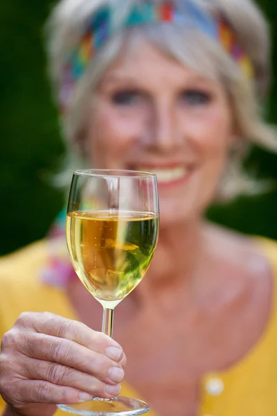 Seniorin stößt mit Weinglas an — Stockfoto