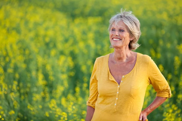 Счастливая пожилая женщина, стоящая на поле — стоковое фото