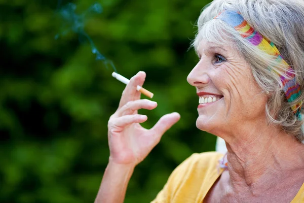 Mulher sênior fumar cigarro enquanto olha para fora no parque — Fotografia de Stock
