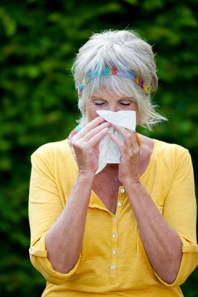 Senior vrouw neus waait in papieren zakdoekje — Stockfoto