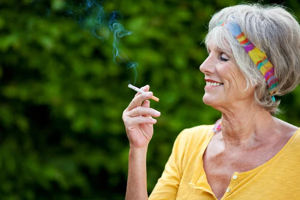 Mulher Sênior fumando cigarro no parque — Fotografia de Stock