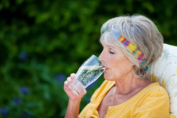 Seniorin trinkt Sprudelwasser im Park — Stockfoto