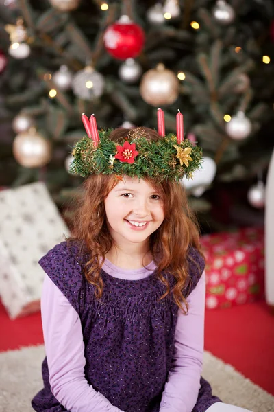 Menina sorridente vestindo uma coroa de vela de Natal — Fotografia de Stock