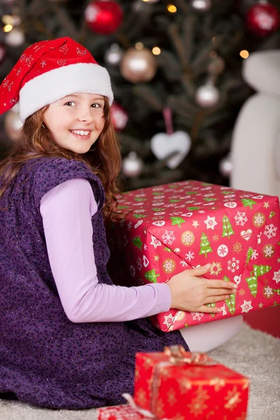 Menina alegre com um grande presente de Natal vermelho — Fotografia de Stock