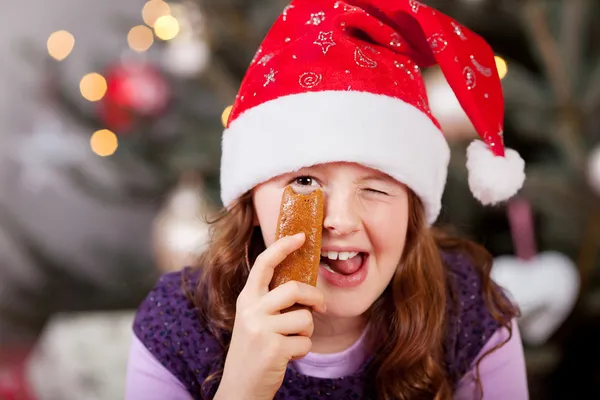 Menina em um chapéu de Papai Noel dando uma piscadela alegre — Fotografia de Stock