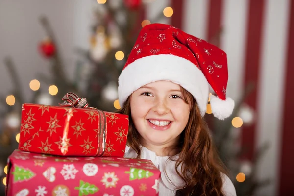 Sonriente chica en un sombrero de Santa con sus regalos —  Fotos de Stock