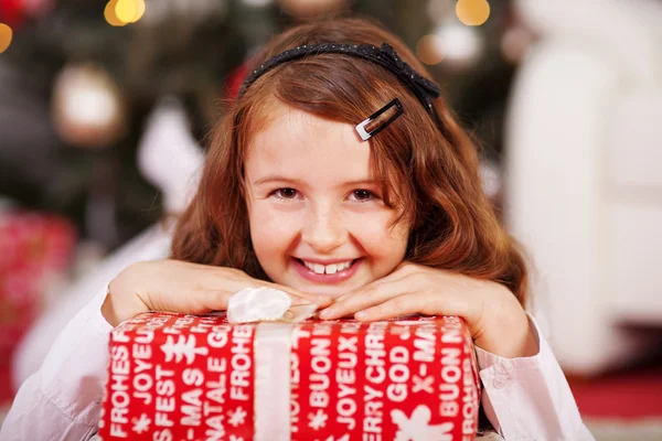 Lachende jong meisje met een rode kerstcadeau — Stockfoto