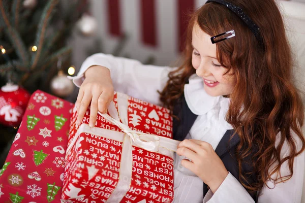 Aufgeregtes kleines Mädchen macht ihr Weihnachtsgeschenk rückgängig — Stockfoto