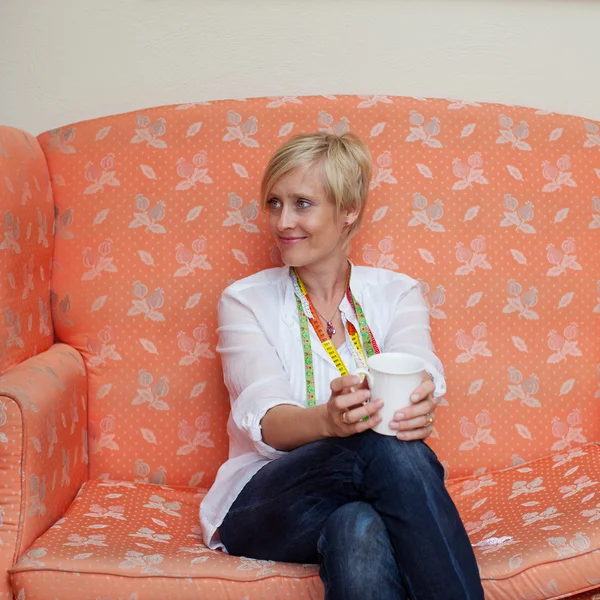 Designer Holding Coffee Mug While Looking Away On Sofa — Stock Photo, Image