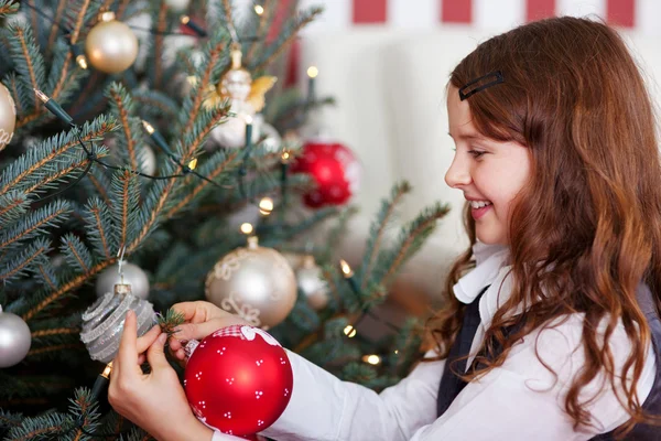 Happy girl hanging Christmas baubles Royalty Free Stock Photos