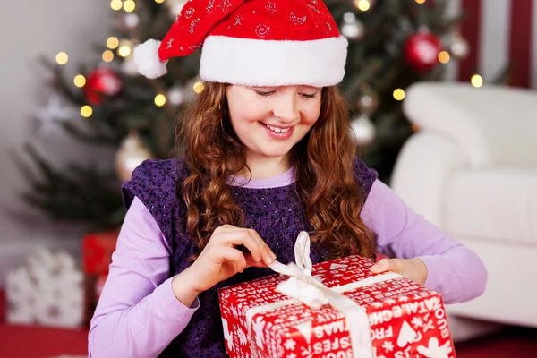 Jovencita desenvolviendo su regalo de Navidad Imagen de archivo
