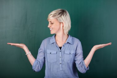 Blond Woman With Empty Palms Against Chalkboard clipart