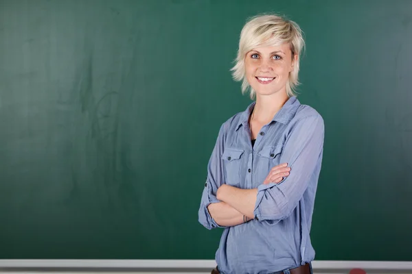 Confiante jovem professora na frente de Chalkboard — Fotografia de Stock