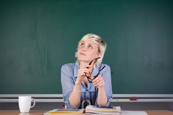 Young woman sitting in front of the blackboard — Stock Photo, Image