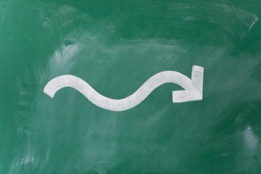 wavy arrow drawn on blackboard representing fluctuation in busin clipart