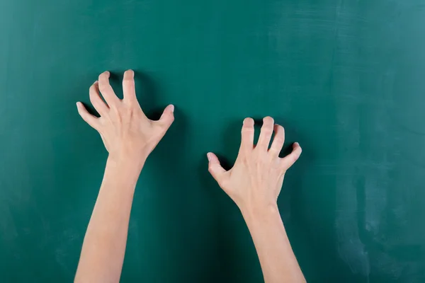 Hands claw at blackboard — Stock Photo, Image