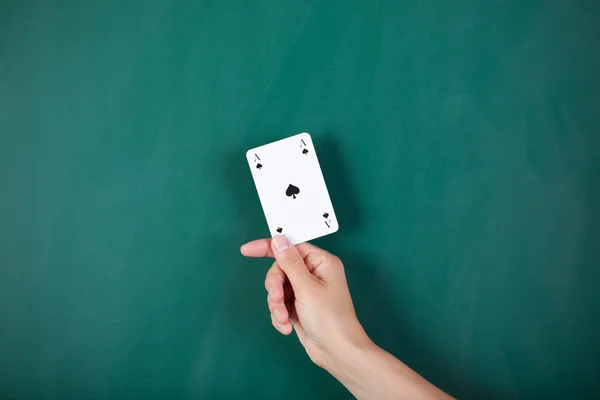 Woman's hand holding ace card against green board — Stock Photo, Image