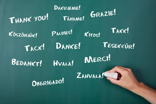 Woman's hand writing Thank You in various languages on chalkboar — Stock Photo, Image