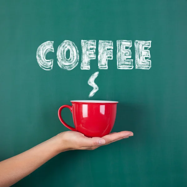 Woman's hand holding coffee cup with coffee written on chalkboar — Stock Photo, Image